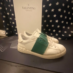 Valentino Garavani sneakers - Snygga Valentino Garavani sneakers i vitt med en grön detalj över sidan. Skorna har en klassisk design med snörning och en bekväm sula. Perfekta för en stilren look.Kan sänka priset vid snabb affär🔥🍾