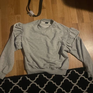 Grå tröja från Gina Tricot - Säljer en snygg grå tröja från Gina Tricot i storlek XS. Tröjan har långa ärmar med volangdetaljer som ger en trendig touch. Perfekt för en stilren look. Hör av dig vid intresse! 💫tröjan är enbart använd en gång!