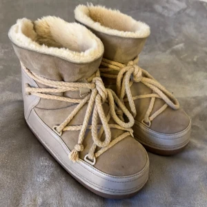 Beiga inuikii skor - Säljer ett par supermysiga beige vinterboots från Inuikii. De är fodrade med mjuk päls och har en snygg snörning framtill. Perfekta för kalla vinterdagar när du vill hålla fötterna varma och stiliga. Använda men i bra skick. Har några små slitningar här och där men inget som märks tydligt, storlek 38, är i den bredare modellen❤️Nypris ligger runt 3799kr❤️Skriv om du undrar något