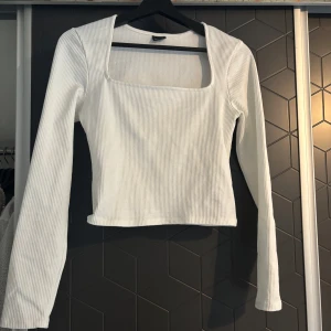 Vit ribbad topp - Snygg vit ribbad topp med fyrkantig halsringning och långa ärmar. Perfekt för en stilren look.