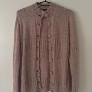 Rosa stickad kofta från Vila - Säljer en söt rosa stickad kofta från Vila med dekorativa knappar och ett fint mönster längs kragen och knappslån. Perfekt för kyliga dagar och ger en mysig känsla. 💖Jag skulle säga att den är lite mer rosa i verkligheten