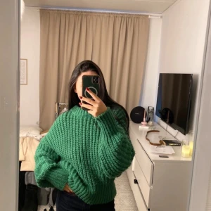 Grön stickad tröja - Säljer en mysig grön stickad tröja med långärmad design. Perfekt för kyligare dagar med sin tjocka och varma känsla. Tröjan har en ribbad struktur som ger en stilren look.