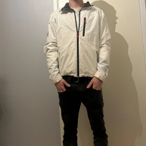 Vit vindjacka från Helly Hansen - En vitt snygg jacka från Helly Hansen. Den är lite smutsig så tvättar innan jag postar den. Det är typ färg som har lossnat innanför tyget som ni ser på bild 5. Hör av er vid frågor. 