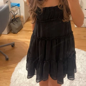 Svart klänning med volanger - Säljer en söt svart klänning med volanger och smala axelband. Perfekt för en sommar look. 