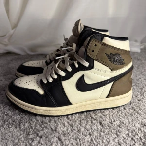 Jordan 1 Dark Mocha - Air Jordan 1 i färgen Dark Mocha. Dessa sneakers har använts och visar några tecken på användning men är i ok skick med mycket kvar i både komfort och stil. Ett perfekt val för sneakerentusiaster eller den som söker ett par klassiska och exklusiva Jordan 1. Storlek 40.