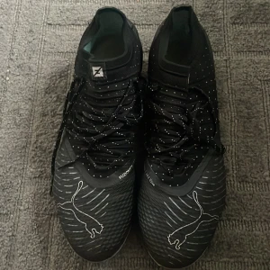  Puma Future Elite fotbollsskor - Säljer ett pa svarta Puma Future ELITE, nypris 2500!!!. Skorna har en mönstrad sula med dobbar för bra grepp på planen, fungerar både på konstgräs och naturgräs. Storlek 41, UK 7,5. Skorna är använda men inte mycket och är i väldigt bra skick!!! Lägre priser kan diskuteras.