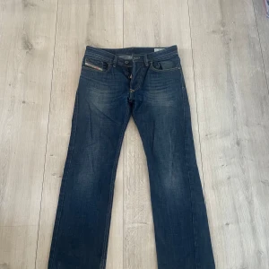 Mörkblå jeans från Diesel - Snygga mörkblå jeans från Diesel, modell Larkee. De har en klassisk straight passform med knappgylf och diskreta slitningar för en cool look. Perfekta för en avslappnad stil.