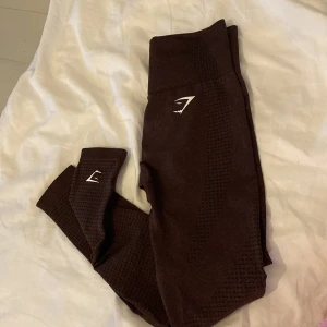 Gymshark tights - Säljer ett par brun/röda leggings från Gymshark i nyskick. Materialet är stretchigt och bekvämt. Logga finns på midjan och benet