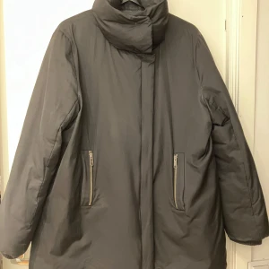 Dunjacka med stor krage - Svart dunjacka med stor krage som en snygg detalj. St L. Yttertyg: 55% polyester & 44% bomull. I bra skick endast ett litet hål på ena armen, se bild.