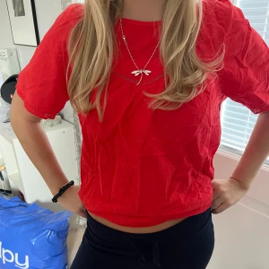 Röd blus med spetsdetaljer - Snygg röd blus med korta ärmar och fina spetsdetaljer vid halsen och nederkanten. Perfekt till jul.