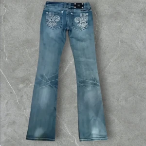 Miss me Blå bootcut jeans med broderade detaljer -  Miss me Snygga blå bootcut jeans med coola broderade detaljer på bakfickorna. De har en klassisk femficksdesign och en lätt slitning för en trendig look. Perfekta för både vardag och fest! 🕺