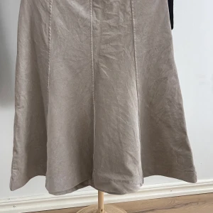 Grå kjol från H&M - Säljer en stilren grå, klockad kjol från H&M i storlek 38. Kjolen har en dragkedja och knapp på sidan för enkel på- och avtagning. Perfekt för både vardag och festliga tillfällen. Materialet känns mjukt och bekvämt.