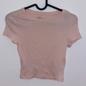 Ljusrosa ribbad topp - Säljer en söt ljusrosa ribbad topp från VS. Den är kortärmad och har en tight passform, perfekt för sommardagar. Toppen är i bra skick och passar till både vardag och fest. Superfin att matcha med jeans eller kjol!