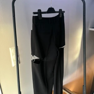 Svarta kostymbyxor  - Svarta kostymbyxor med cool detalj från NAKD! Använda 1 gång, nypris 449