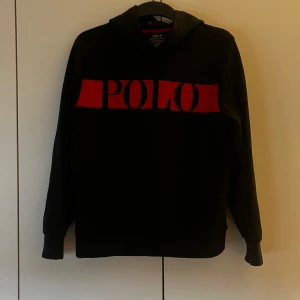 Svart hoodie från Polo Ralph Lauren - Säljer en snygg svart hoodie från Polo Ralph Lauren med röd logga framtill. Den har långa ärmar och en klassisk luva. 