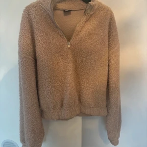Beige fleece tröja med dragkedja - Mysig beige fleece tröja med halv dragkedja. Perfekt för kyliga dagar när du vill hålla dig varm och bekväm. Tröjan har en avslappnad passform och är supermjuk. Ett måste för höst- och vintergarderoben! Knappt använd!
