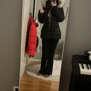 Svart dunjacka från Polo Club - Säljer en snygg svart dunjacka från Polo Club i storlek 36. Jackan har en fluffig pälsfodrad huva och dragkedja framtill. Perfekt för kalla vinterdagar! Den är i mycket bra skick och har praktiska fickor med dragkedjor.