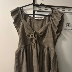 Beige blus från 157 - Säljer en superfin beige blus från 157 i storlek S. Den har en söt knytning framtill och volangdetaljer vid ärmarna. Perfekt för vår och sommar! 💕