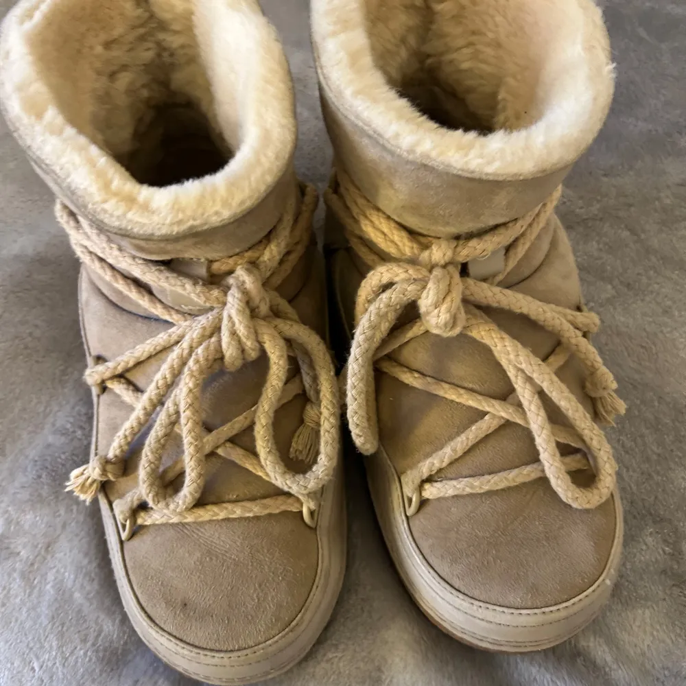 Säljer ett par supermysiga beige vinterboots från Inuikii. De är fodrade med mjuk päls och har en snygg snörning framtill. Perfekta för kalla vinterdagar när du vill hålla fötterna varma och stiliga. Använda men i bra skick. Har några små slitningar här och där men inget som märks tydligt, storlek 38, är i den bredare modellen❤️Nypris ligger runt 3799kr❤️Skriv om du undrar något. Skor.