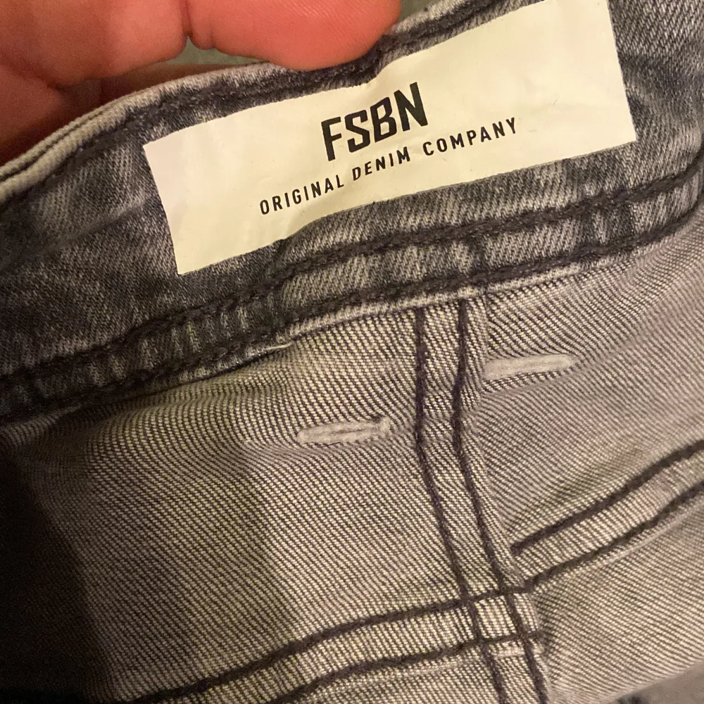 Säljer ett par grå jeans från FSBN i bra skick. De har en snygg, tvättad look med en liten reva på ena benet för en cool touch. Perfekta för vardagsbruk eller en avslappnad utekväll. Midjan är normal och passformen är slim, vilket ger en modern och stilren siluett.. Jeans & Byxor.