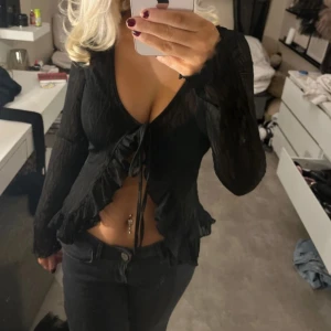 Svart topp med knytning - Snygg svart topp med långa ärmar och volangdetaljer framtill. Toppen har en knytning vid bysten. Perfekt för en utekväll eller fest!💕aldrig använt