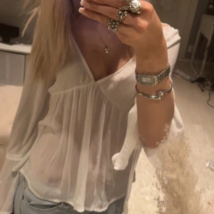 Vit blus med v-ringning - Säljer en superfin vit blus med v-ringning och långa ärmar. Den är gjord i ett lätt och luftigt material, perfekt för både vardag och fest. Blusen har en lös passform som ger en avslappnad look. Passar perfekt till jeans eller kjol!🩷🩷
