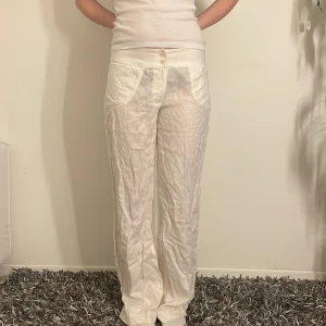 Vita linnebyxor från GANT - Säljer ett par snygga vita linnebyxor från GANT i nytt skick. De är lågmidjsde med en lös passform, perfekta för sommaren. Byxorna har en enkel design med knappar framtill och är superbekväma. Perfekta för en avslappnad men stilren look! 