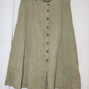 Grön kjol från Geisha - Säljer en snygg grön kjol köpt i Portugal på en secondhandbutik från Geisha i storlek 44. Kjolen har knappar hela vägen ner och är i ett mjukt material som känns bekvämt. Perfekt för både vardag och lite finare tillfällen. Den har en klassisk stil som aldrig går ur modet. Då den är lite stor har jag använt säkerhetsnålar för att vika in den vid höfterna, tips till dig som är intresserad men har en lite mindre storlek!!