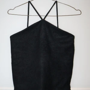 Svart ribbad linnetopp från Gina Tricot - Snygg svart ribbad linnetopp från Gina Tricot i storlek S. Perfekt för sommardagar eller som ett lager under en jacka. Den har smala axelband och en enkel design som gör den lätt att matcha med olika outfits.