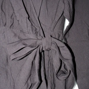 Svart omlottklänning med knytband - Snygg svart omlottklänning i medium storlek. Den har ett knytband i midjan för en justerbar passform och långa ärmar. Perfekt för både vardag och festliga tillfällen. Aldrig använd och därför säljer jag den nu! ☺️