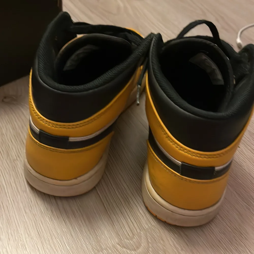 Säljer ett par Nike Air Jordans i gult och svart med vita detaljer. Skorna har en klassisk hög modell med snörning och är i bra skick. Perfekta för både vardag och fest! 🏀. Skor.