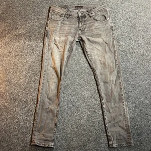 Grå jeans från Nudie - Säljer ett par grå jeans från Nudie i bra skick. De har en slim passform i storleken W33 L30. Bra skick. 