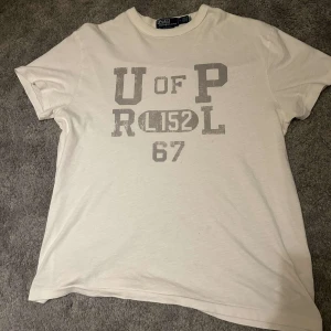 Vit t-shirt från Polo Ralph Lauren - Vit Ralph lauren tröja med ett riktigt unikt tryck. Tröjan är i nyskick den är bara tvättad 1 gång, vid frågor skriv så svarar vi på dina frågor.