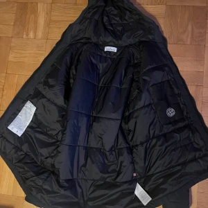 Stone Island svart vinterjacka  - Säljer en svart vinterjacka från Stone Island. Mycket bra skick och varm. Jackan har en praktisk luva och dragkedja framtill. Perfekt för kalla vinterdagar, och den är långärmad. Storlek: XL-L Nypris: 9250kr