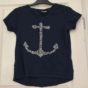Marinblå t-shirt med ankarmotiv - Snygg marinblå t-shirt från Only med ett stort vitt ankarmotiv på framsidan. ⚓️ Storlek XS