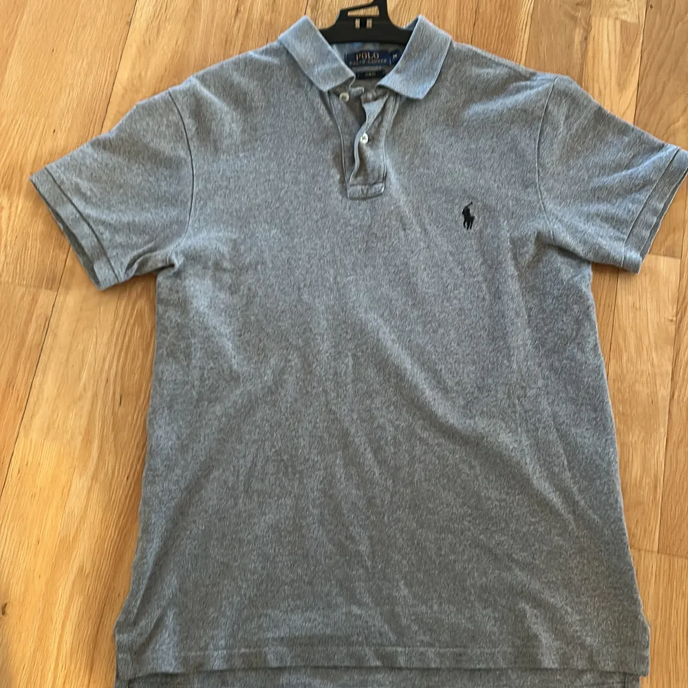 Snygg grå pikétröja från Ralph Lauren med klassisk krage och knappar. Perfekt för en stilren look. Ny pris kostar den 1500kr såklart äkta. Paidat.