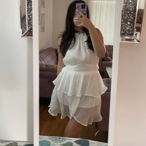 Vit ärmlös klänning - Säljer en söt vit ärmlös klänning med volanger. Perfekt för sommarens alla tillfällen. Klänningen har en luftig passform och ett fint fall som ger en romantisk känsla. Passar perfekt för en dag i solen eller en kväll ute. 💫