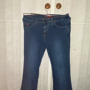 Blå jeans från Forza - Snygga vintage y2k blå jeans från Forza med röd söm och klassisk femficksdesign. Perfekta för en avslappnad stil. De har en bootcut-stil som ger en retro känsla. Från USA. Säljer de för att de inte passade mig