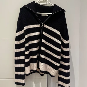 Randig svart och vit kofta från sweewe - Säljer en snygg randig kofta från H&M i svart och vitt. Den har en dragkedja framtill och är ribbad i materialet. Perfekt för en stilren look. Passar bra till både jeans och kjol.