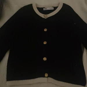 Svart kofta från Zara med guldknappar - Säljer en stilren svart kofta från Zara med kontrasterande vita kanter och eleganta guldknappar. Perfekt för att ge en klassisk touch till din outfit. Koftan har långa ärmar och är tillverkad i ett mjukt material. I storlek S, kontakta mig för intresse 🤍🥰