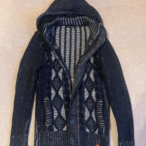 Unik Cardigan Med Päls 🤩💸 - Säljer en fet, svart och vit stickad kofta med huva och knappar. Koftan har ett unikt mönster med rutor och ränder, storlek M, modellen är runt 185. Tveka inte om att skriva om du har några frågor!