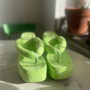 Limegröna platåsandaler - Helt oanvända limegröna platåsandaler i mjuk froté. De har en tjock sula och breda sköna remmar som ger en bekväm passform. Perfekta för att ge en kul färgklick till din outfit. Storlek 40 köpta från NELLY.