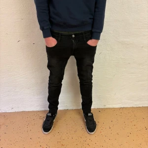 Svarta jeans från Replay - Snygga svarta Replay Anbass jeans i storlek W30 L30. De har en slim passform och är perfekta för en stilren look. Klassisk design med dragkedja och knapp framtill.