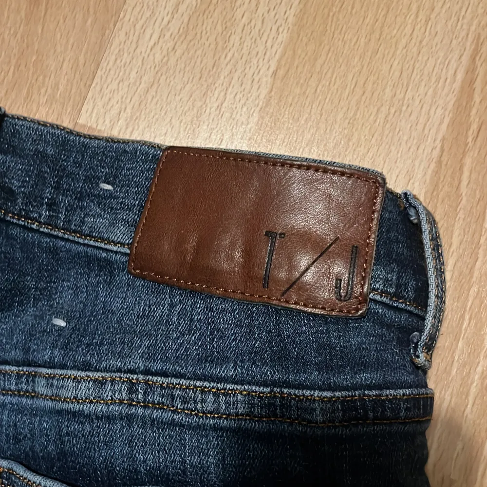 Snygga mörkblå jeans från T/J med slim passform. Tillverkade i Italien, dessa jeans har en klassisk design med dragkedja och knapp. Perfekta för en stilren look.. Farkut & Housut.