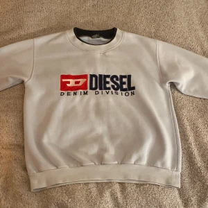 Ljusblå sweatshirt från Diesel - Säljer en vit sweatshirt från Diesel med deras ikoniska logga i rött och blått på framsidan. Tröjan har rund hals och långa ärmar, perfekt för en casual look🔥tröjan har några små fläckar men de borde gå bort i tvätten! Sparsamt använd 