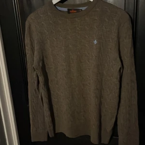 Brun kabelstickad tröja från Morris - Säljer en stilren brun kabelstickad tröja från Morris i 100% merinoull. Tröjan har en diskret broderad logga i ljusblått på bröstet och långa ärmar. Perfekt för kyligare dagar. Pris kan diskuteras vid en snabb affär.