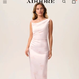 Ljusrosa långklänning från Adoore - Ljusrosa långklänning från Adoore med en asymmetrisk axelbandslös design. mjukt, glansigt material. Prislappen kvar och storlek 38. Otroligt fin!!🩷🩷