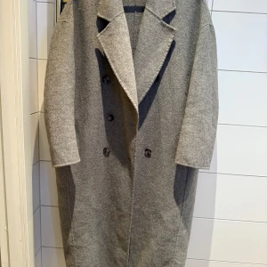 Grå kappa - Snygg grå kappa med dubbelknäppning och breda slag. Perfekt för kyliga dagar med sin stilrena design och långa ärmar. Ett måste för garderoben!