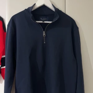 Mörkblå Halfzip från Bondelid - Säljer en helt ny stilren mörkblå tröja från Bondelid med halfzip. Perfekt för en avslappnad look. Tröjan har långa ärmar och en hög krage som ger extra värme.