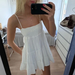Vit Zara klänning - Säljer en söt vit klänning med smala axelband och volangdetaljer. Perfekt för varma sommardagar med sin luftiga design och korta längd. Klänningen har en avslappnad passform som ger en skön känsla. Perfekt för en dag på stranden eller kanske till studenten! 